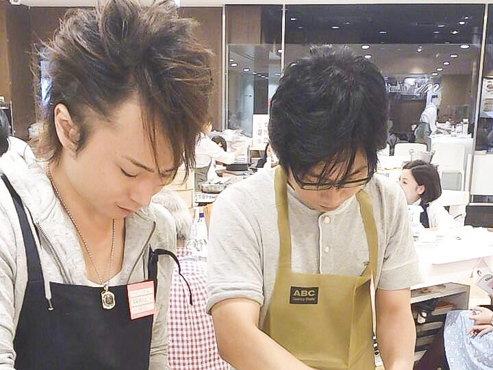 料理学校に通って料理を習う男性2人の画像